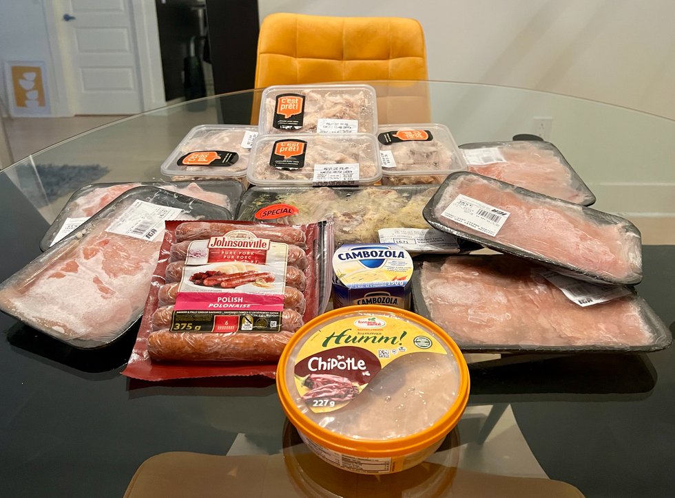 Plusieurs produits d'\u00e9picerie (viandes, fromage et hummus) \u00e9tal\u00e9s sur une table.