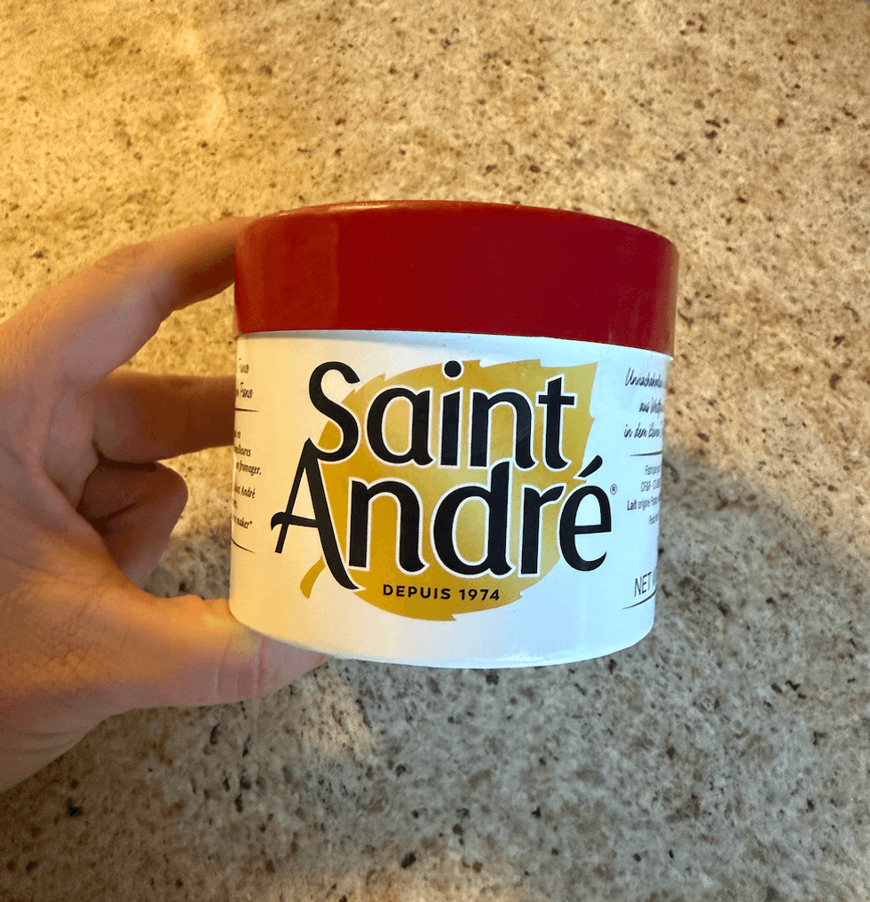 Pot rond de fromage Saint-Andr\u00e9 achet\u00e9 au Liquidation Marie tenu dans une main.