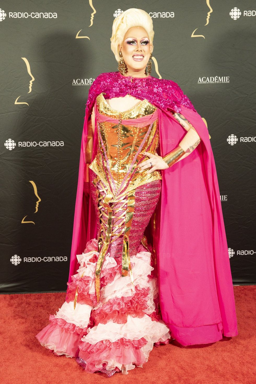 Rita Baga dans une robe rose et or avec une cape aux prix G\u00e9meaux.