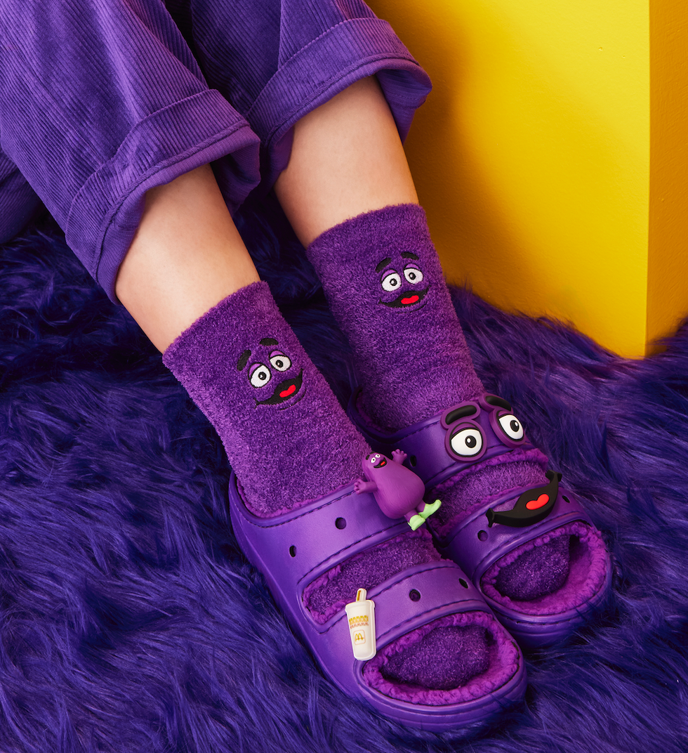 Sandales Crocs mauve \u00e0 l'effigie de Grimace, avec les bas assortis.