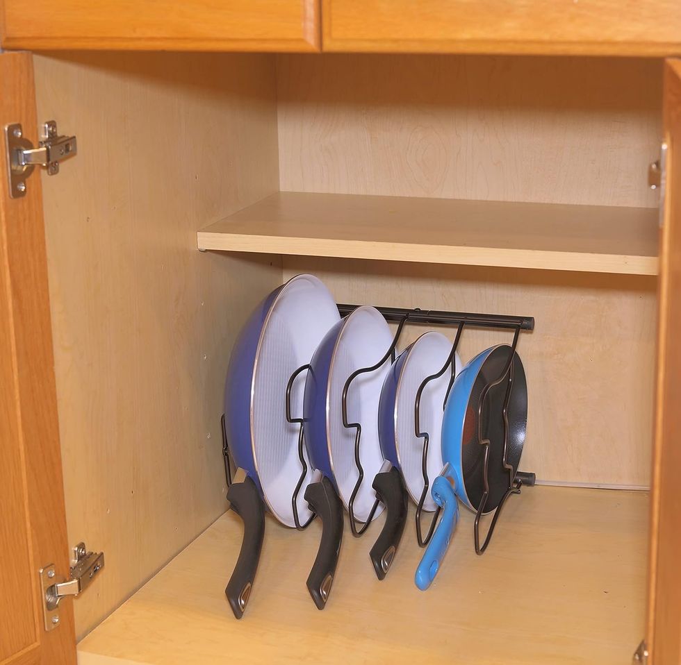 Support de rangement pour casseroles et po\u00eales bronze, plac\u00e9 dans une armoire.