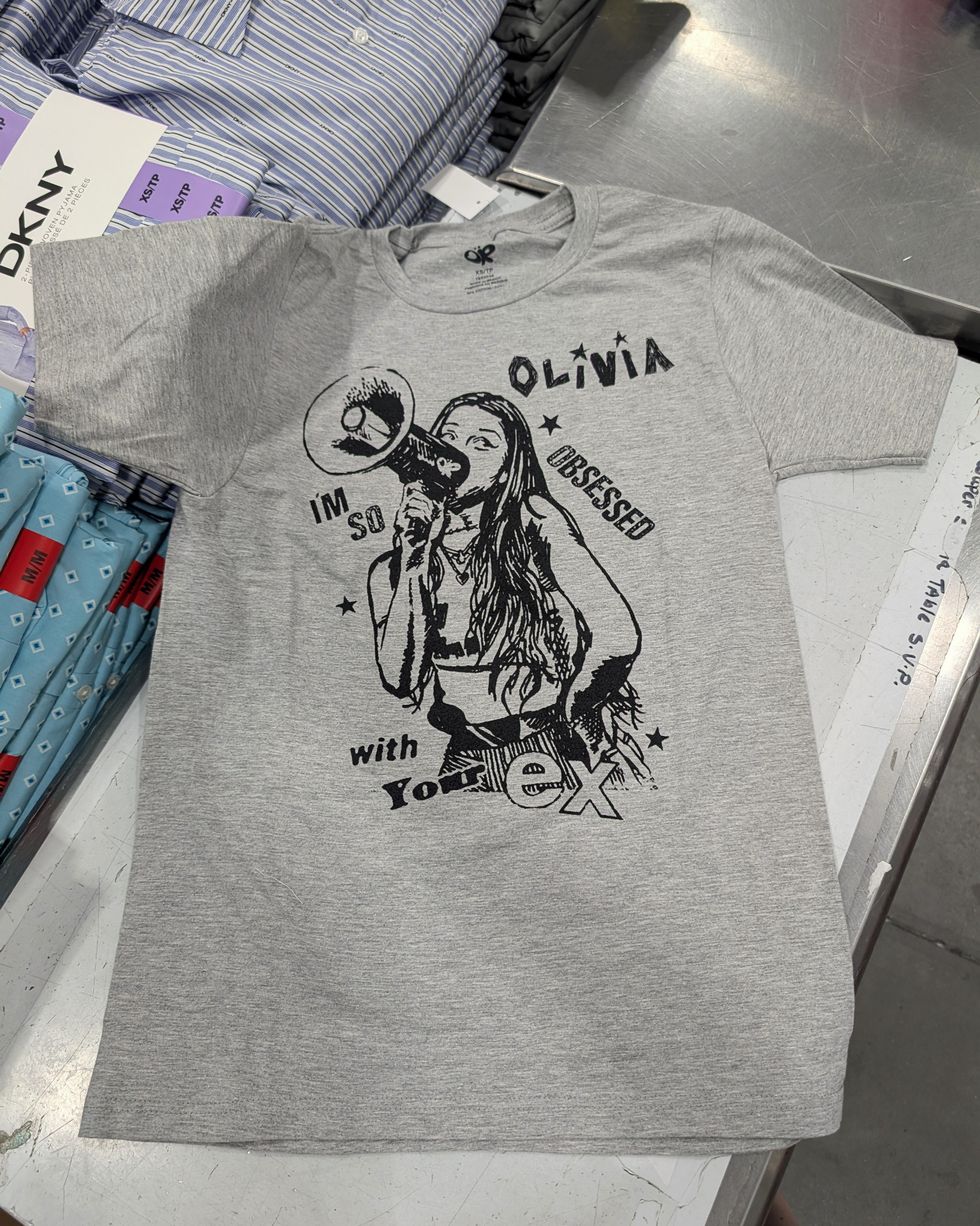 T-shirt gris avec imprim\u00e9 noir d'Olivia Rodrigo vendu dans le rayon mode chez Costco.