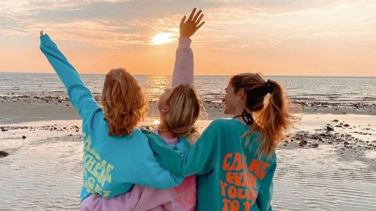 Trois personnes de dos portant des chandails colorés au bord de l'eau à Cape Cod.