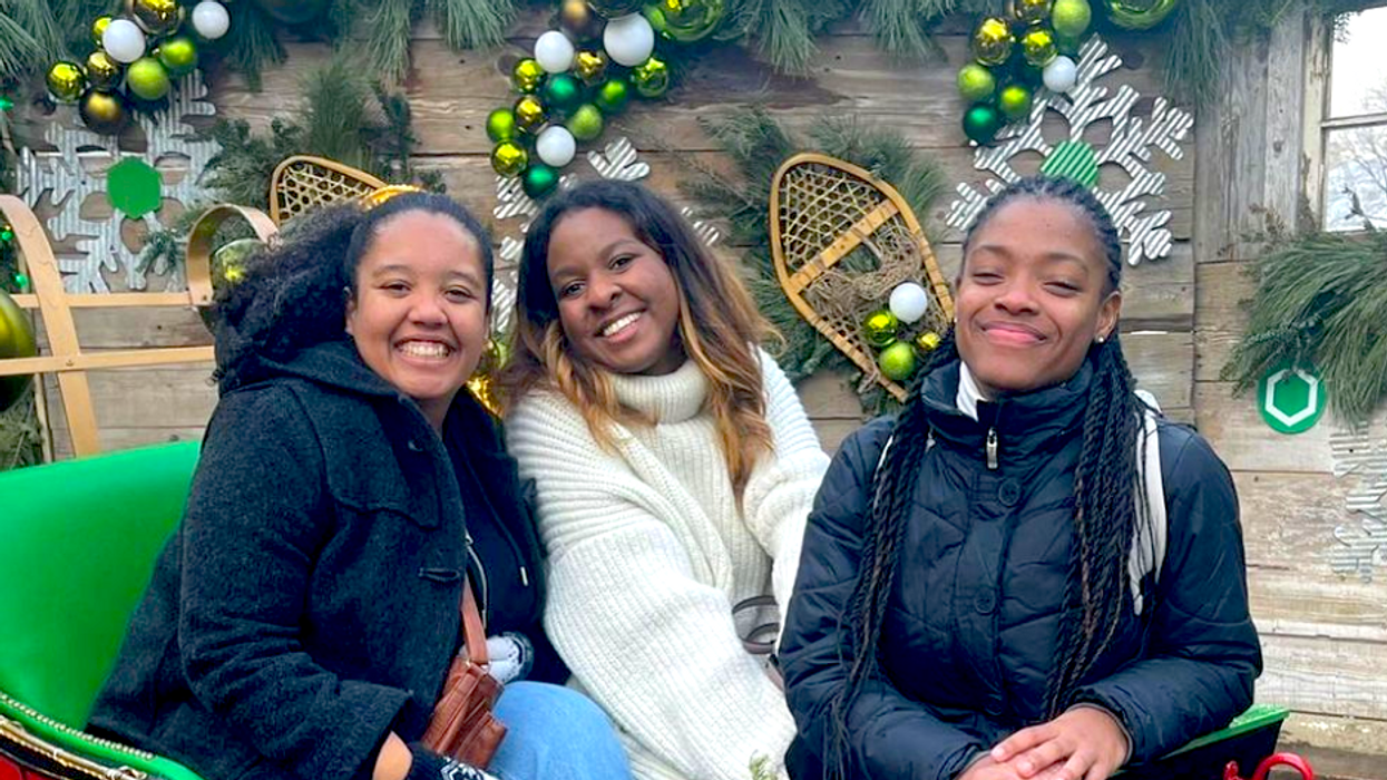 Trois personnes souriantes dans un traineau vert et rouge au Marché de Noël allemand de Québec.