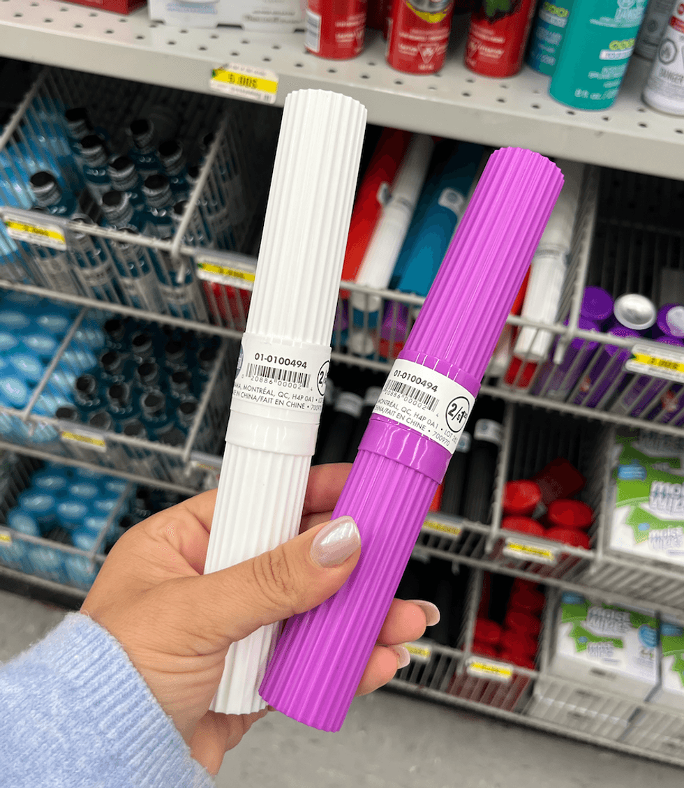 \u200bDeux bo\u00eetiers \u00e0 brosse \u00e0 dents, un mauve et un blanc, en plastique dans une main.