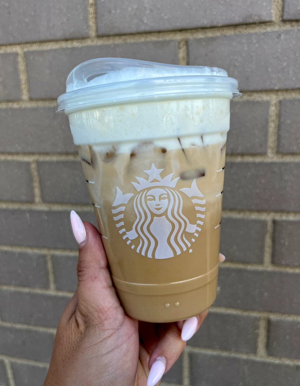 \u200bLatte glac\u00e9 cr\u00e8me au caramel et pomme du Starbucks dans une main.