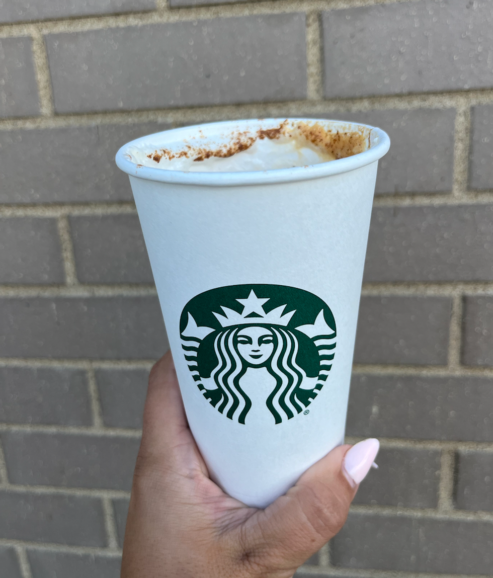 \u200bLatte \u00e0 la citrouille \u00e9pic\u00e9e du Starbucks dans une main.