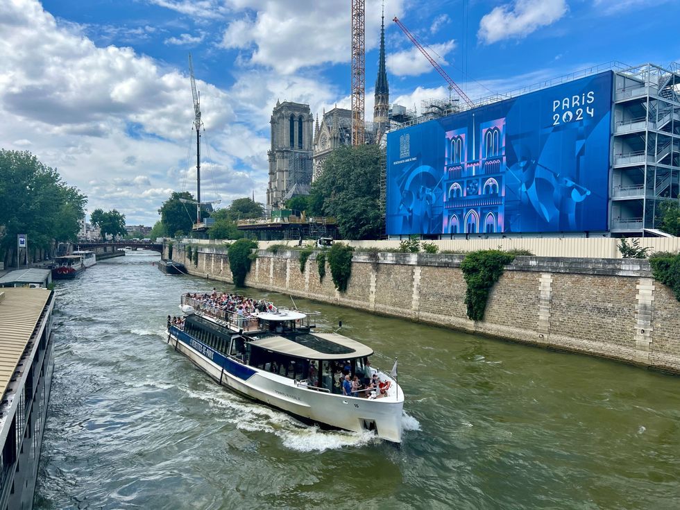 Un bateau-mouche transporte des touristes sur la Seine \u00e0 Paris, pr\u00e8s de la Basilique Notre-Dame en travaux.
