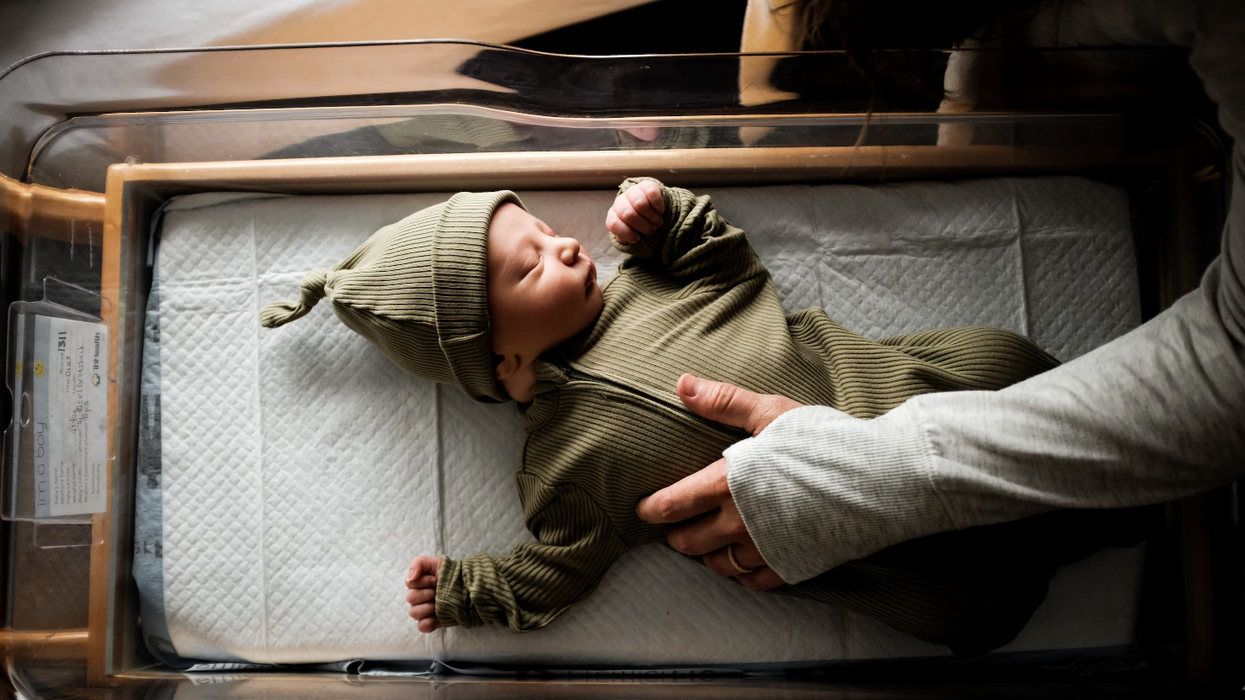 Un bébé avec un bonet vert sans un lit à l'hôpital.