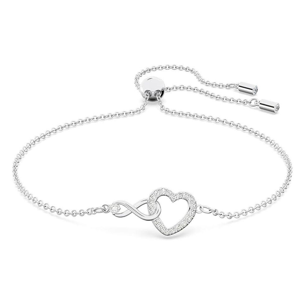 Un bracelet argent\u00e9 avec symbole infini et coeur de marque Swarovski sur fond blanc.