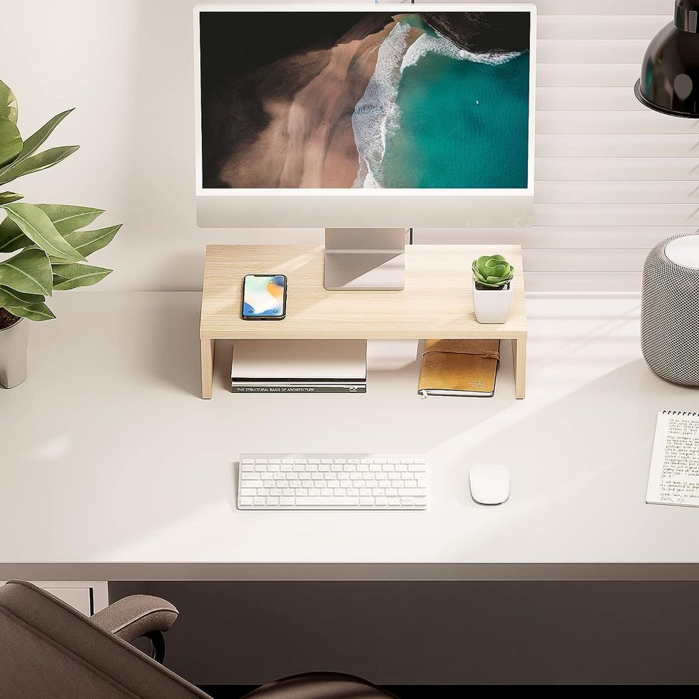 Un bureau de travail avec un \u00e9cran d'ordinateur pos\u00e9 sur un support en bois.