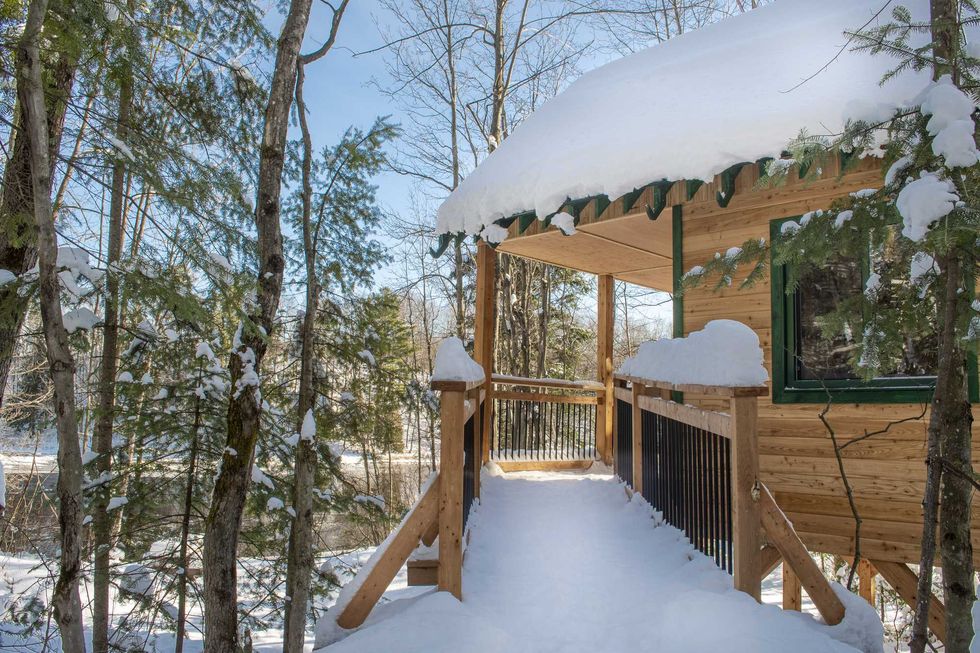 Un chalet rustique dans les bois, recouvert de neige.