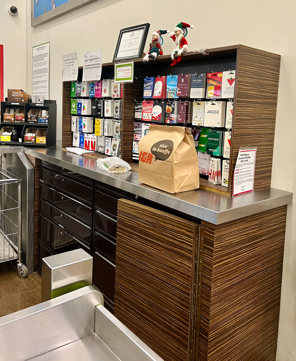 Un comptoir d'accueil chez IGA avec une commande emball\u00e9e dans un sac de papier brun.