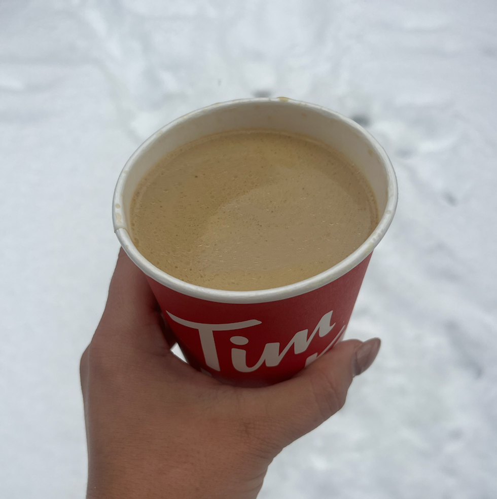 Un latte chocolat blanc et pistache du Tim Hortons dans une main \u00e0 l'ext\u00e9rieur.