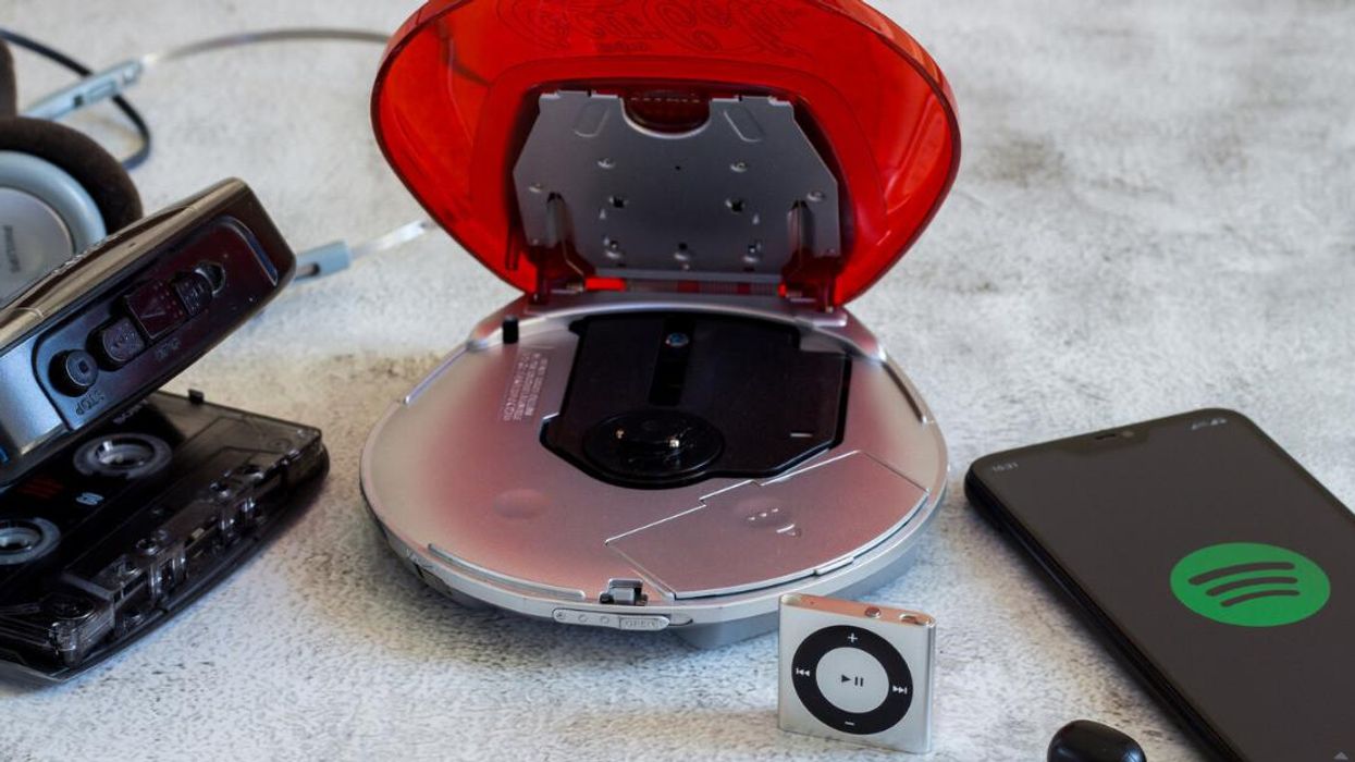 Un lecteur cassette, un lecteur cd, un Ipod Mini et un téléphone avec l'icône de Spotify.