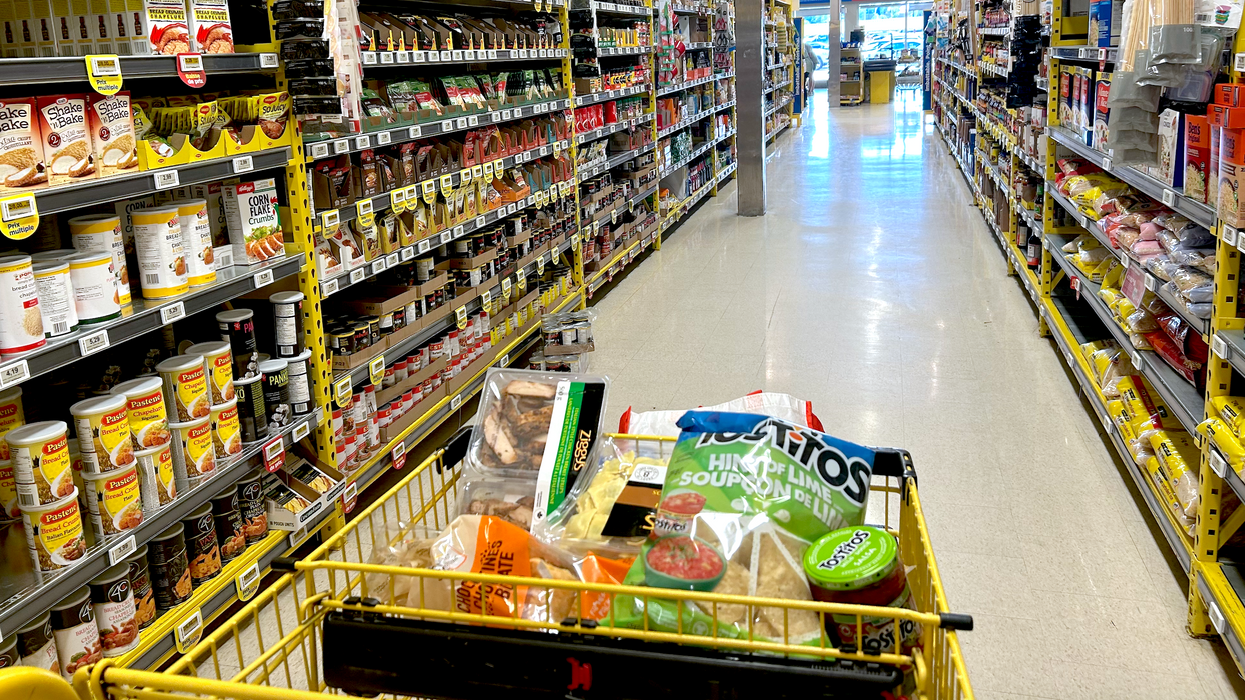 Un panier jaune rempli d'aliments dans une allée du Maxi.