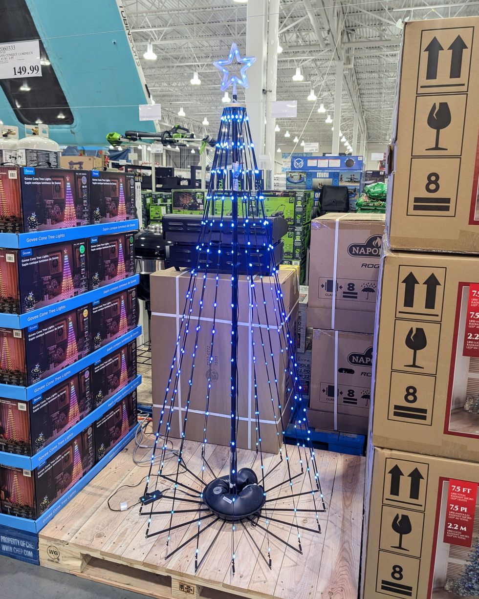Un sapin conique lumineux de 6 pieds en pr\u00e9sentation dans le rayon des articles saisonniers chez Costco.