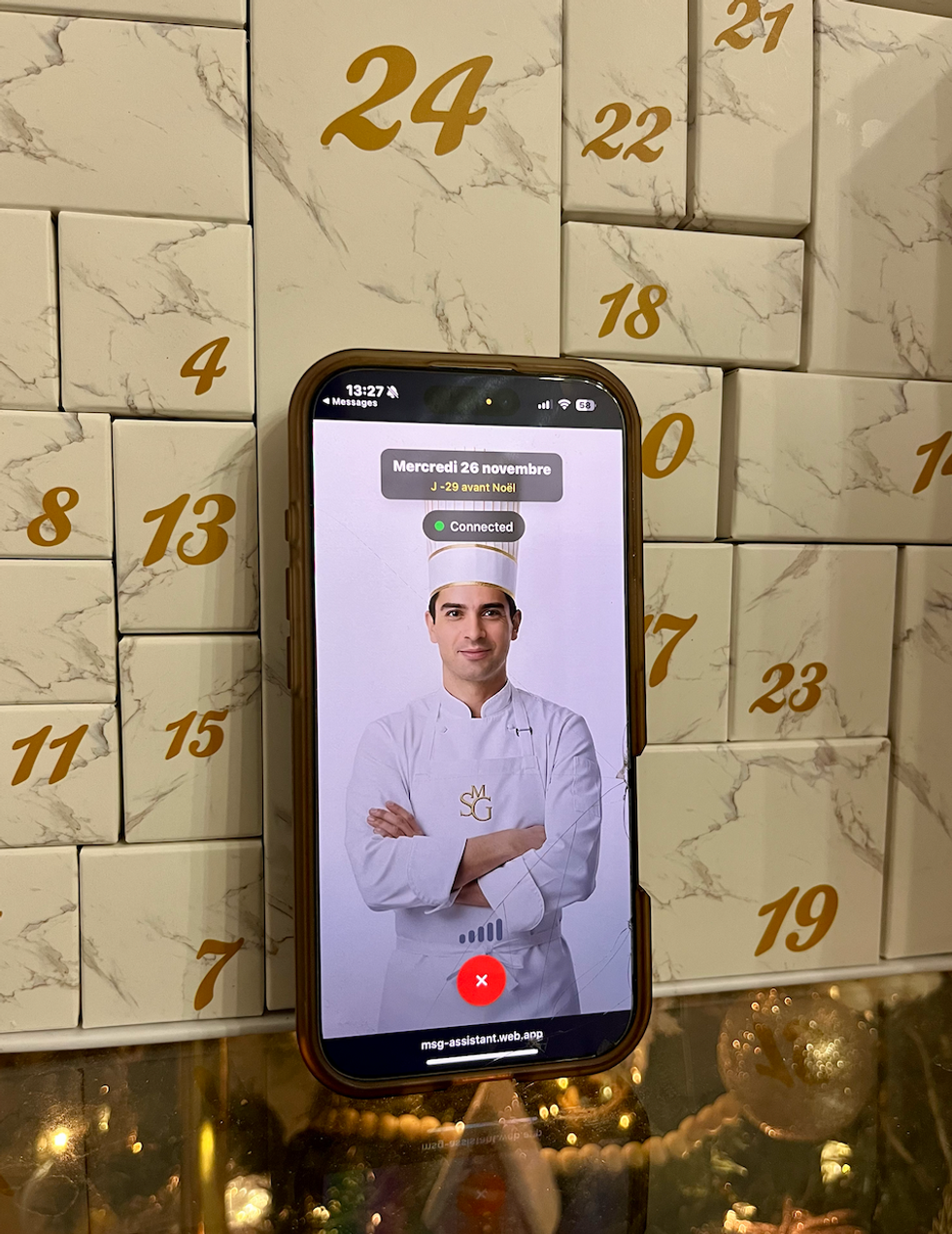 Un t\u00e9l\u00e9phone montre l'agent p\u00e2tissier IA du calendrier de l'avent Mon Secret Gourmand.