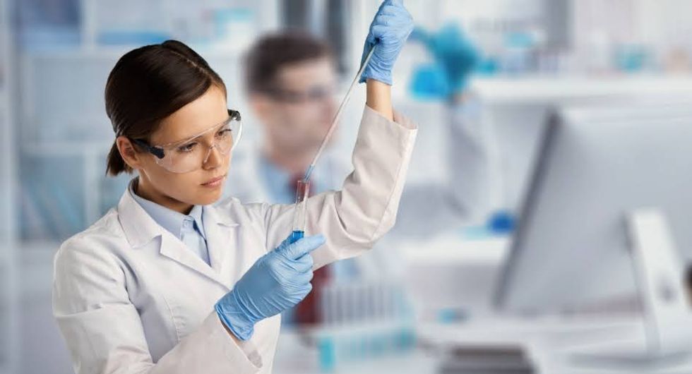 Un\u00b7e scientifique dans un laboratoire utilise une pipette pour remplir un tube \u00e0 essai.