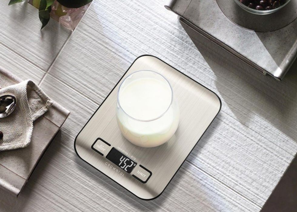 Un verre de lait sur une balance alimentaire d\u00e9pos\u00e9e sur un comptoir de cuisine.