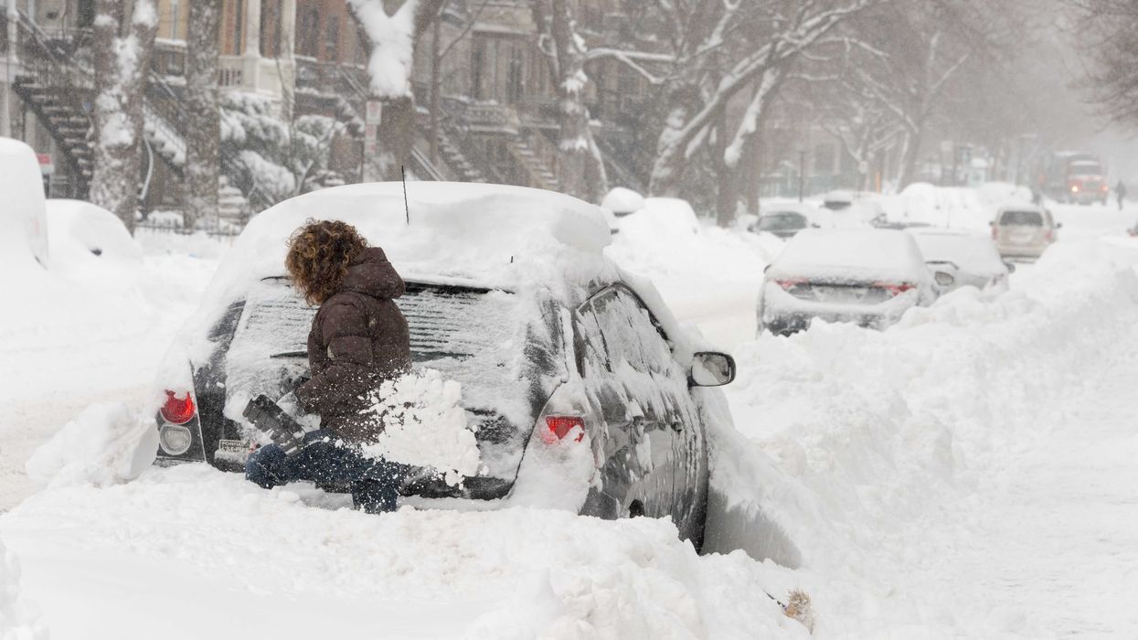 Une femme qui déneige une voiture.