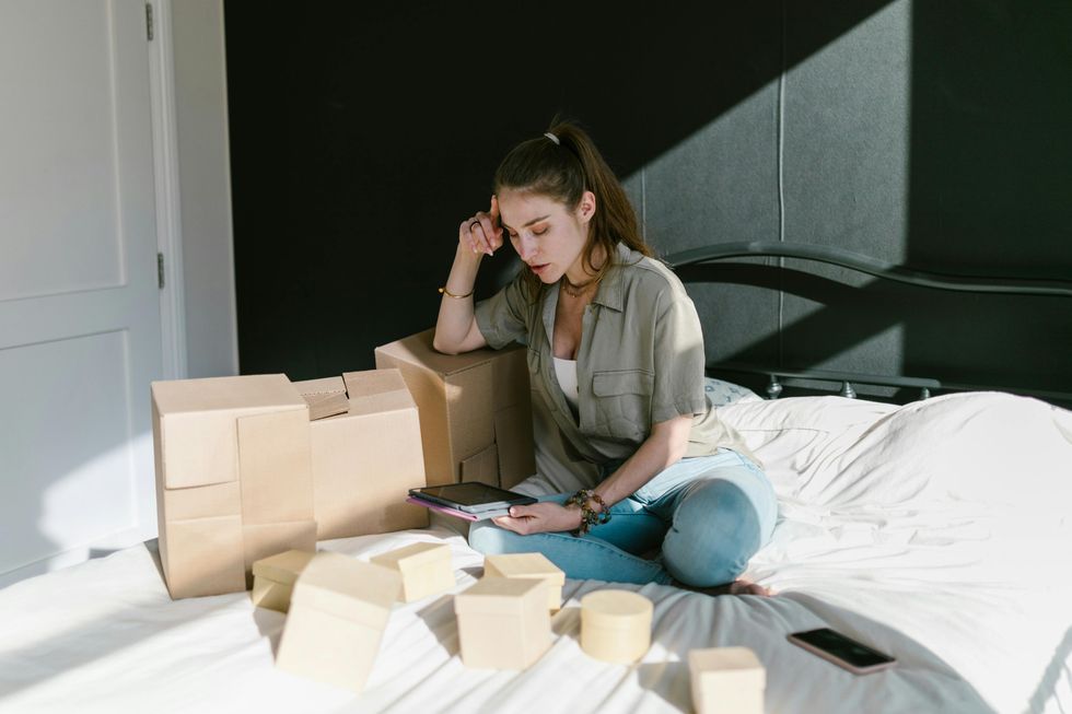 Une femme qui utilise une tablette num\u00e9rique assise sur son lit