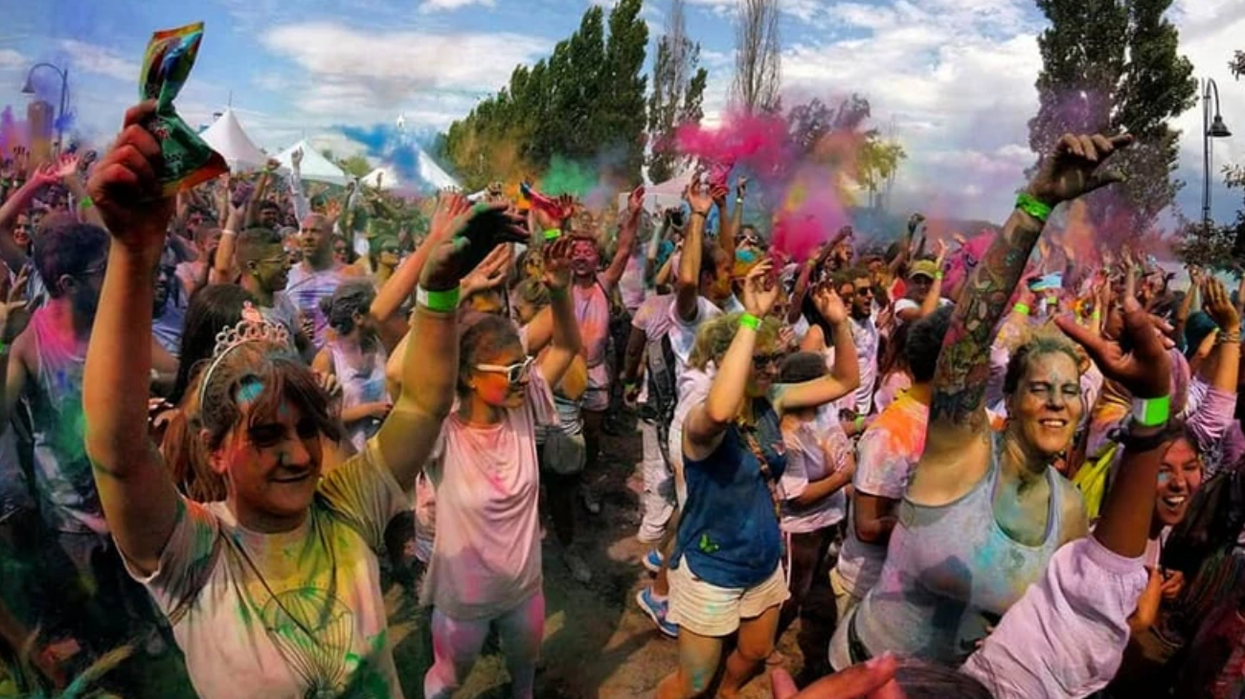 Une foule qui lance des poudres colorés lors d'un festival extérieur.