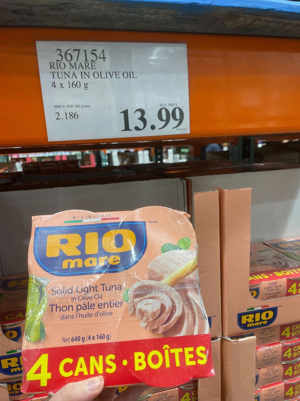 Une main qui tient un paquet de cannes de thon Rio Mare chez Costco.