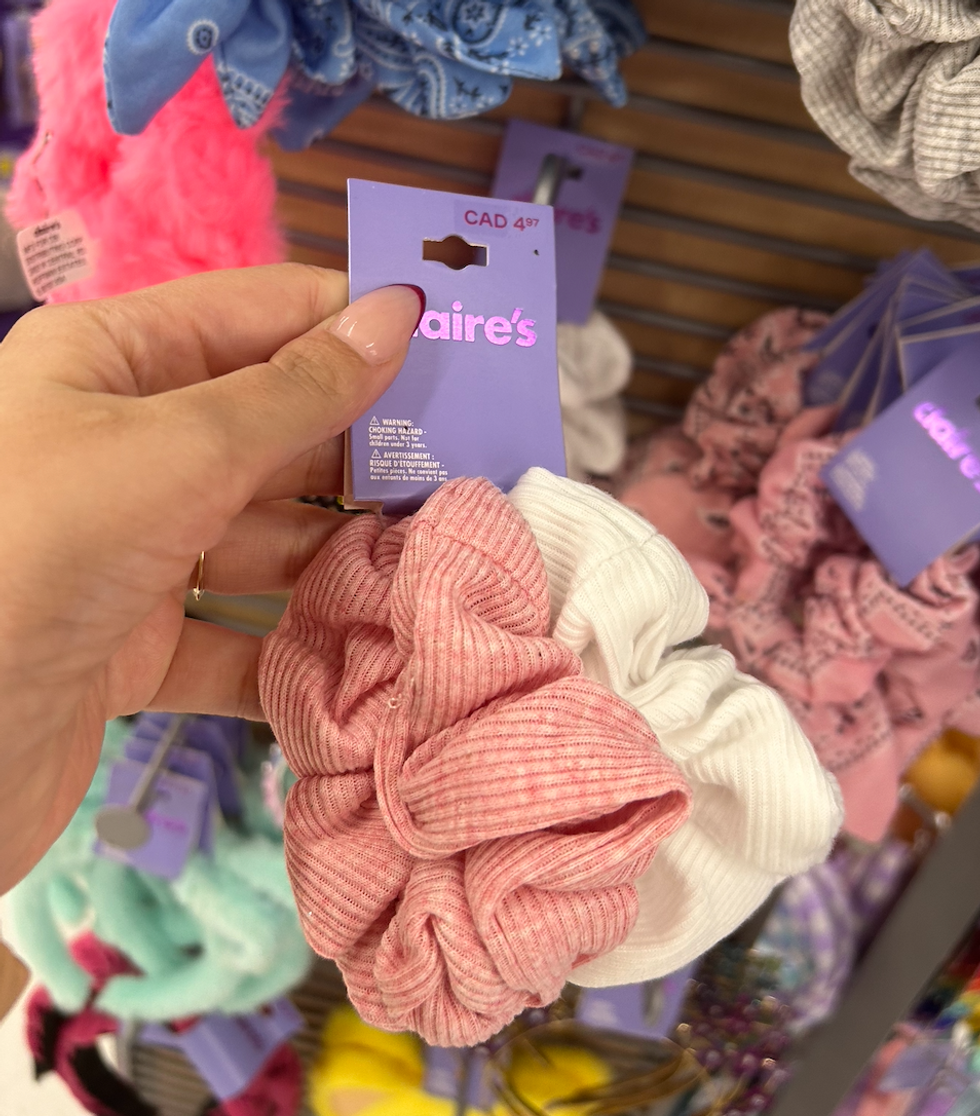 Une main tenant un duo de chouchous roses et blancs de la marque Claire's au Walmart.