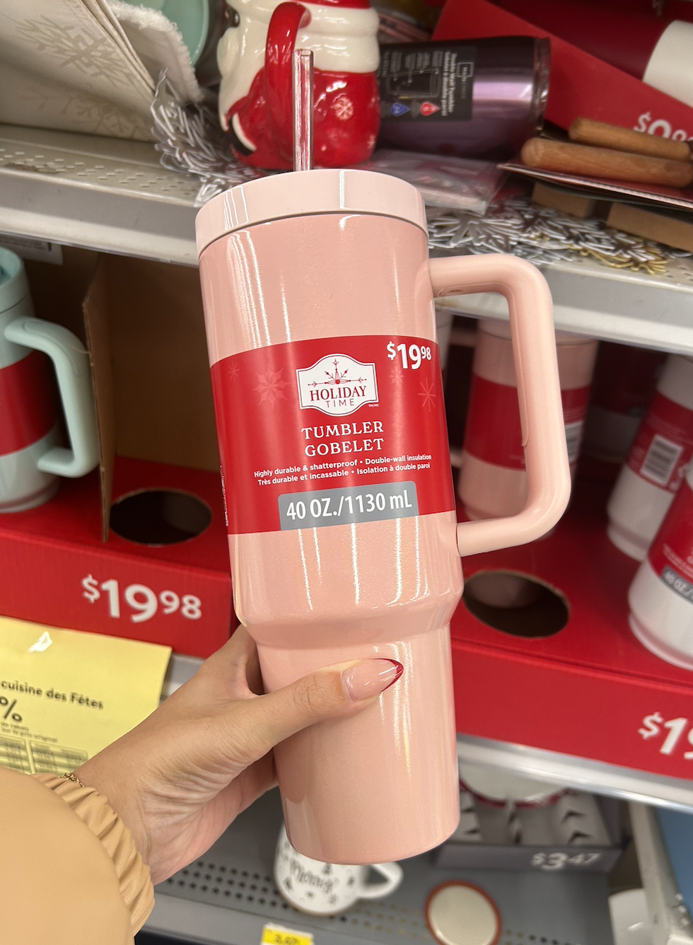 Une main tenant un gobelet rose dans les rayons du Walmart.