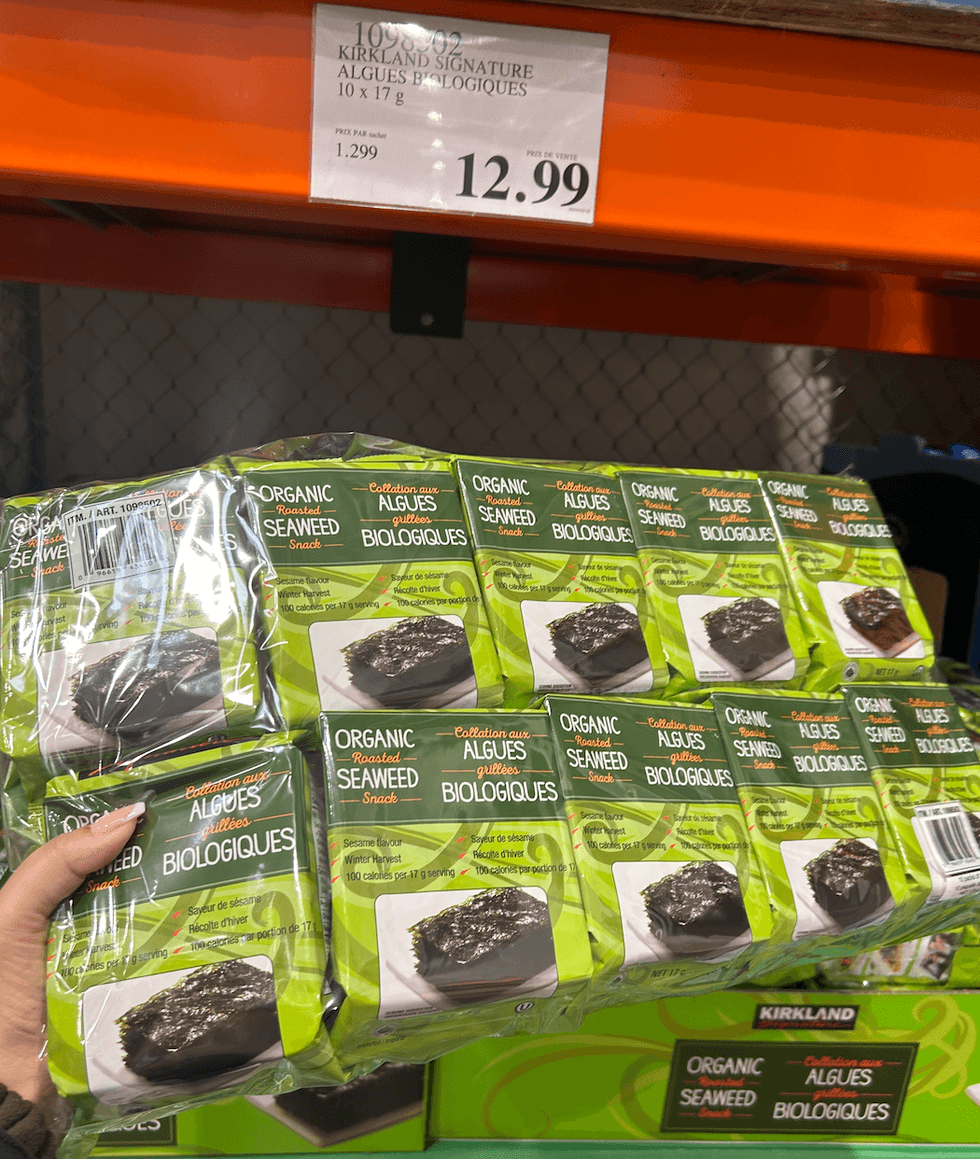 Une main tenant un paquet d'algues biologiques devant un \u00e9talage du Costco.