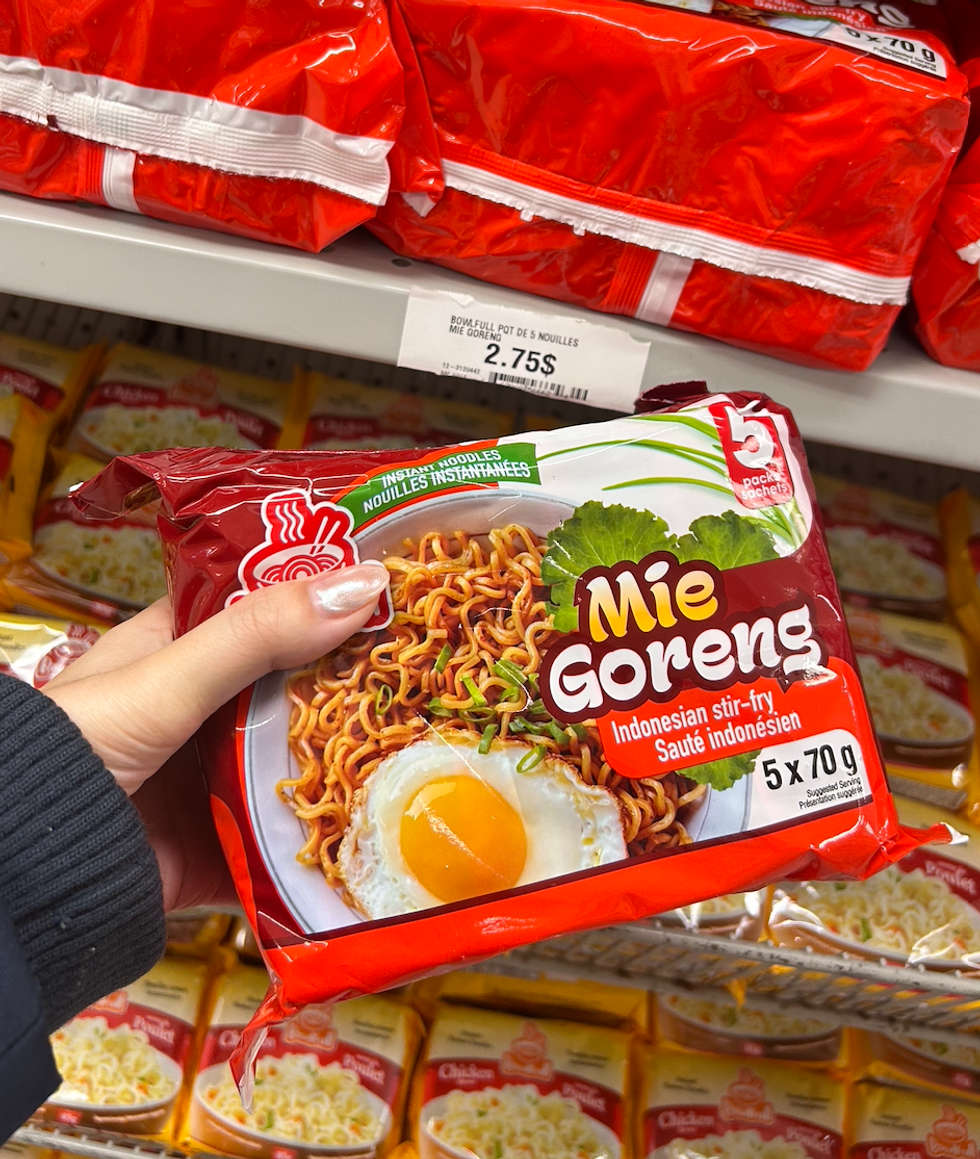 Une main tenant un paquet de 5 sachets de nouilles ramen au Dollarama.