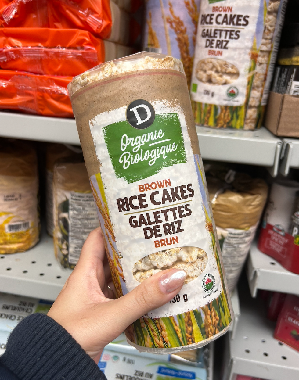 Une main tenant un sac de galettes de riz brun au Dollarama.