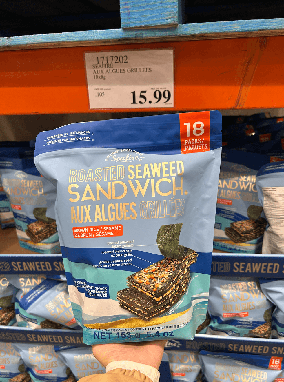 Une main tenant un sac de sandwichs aux algues grill\u00e9es Seafire devant l'\u00e9talage chez Costco.