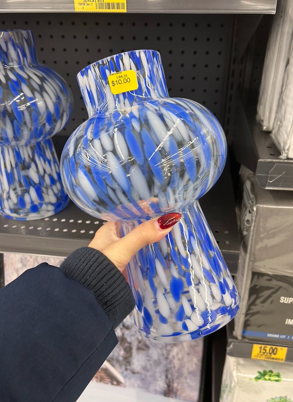 Une main tenant un vase en verre bleu et blanc au Tigre G\u00e9ant.