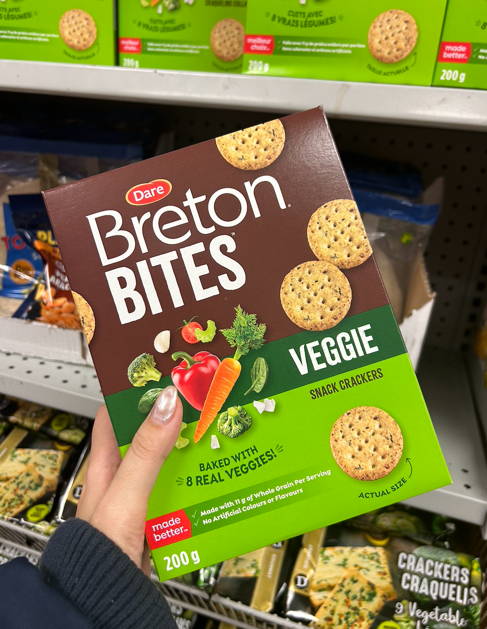 Une main tenant une boite de craquelins Breton Veggie Bites de Dare.