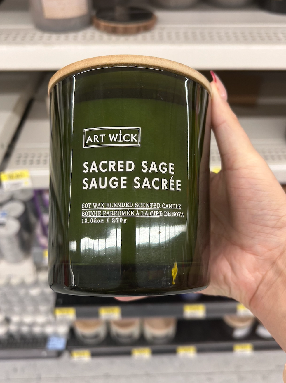 Une main tenant une chandelle pour la maison \u00e0 la sauge, contenant 370 g de cire de soya.