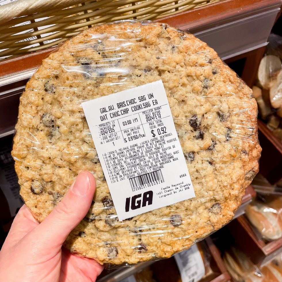 Une main tenant une grosse galette \u00e0 l'avoine et aux p\u00e9pites de chocolat.