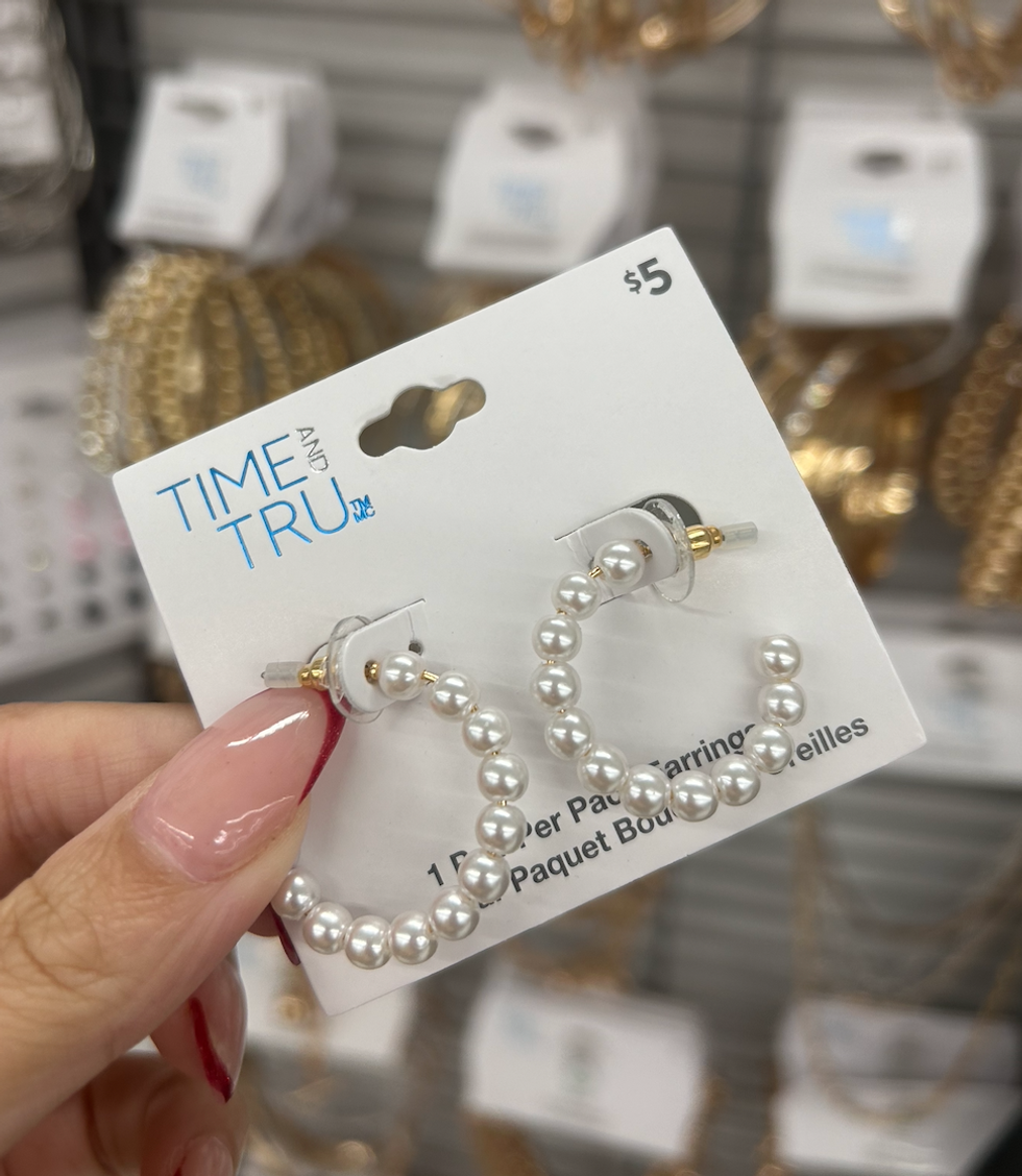 Une main tenant une paire de boucles d'oreilles au Walmart.