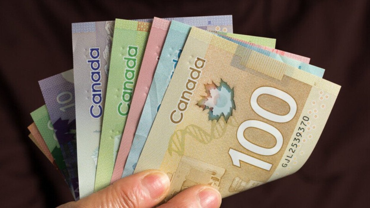 Une main tient des billets d'argent canadien.