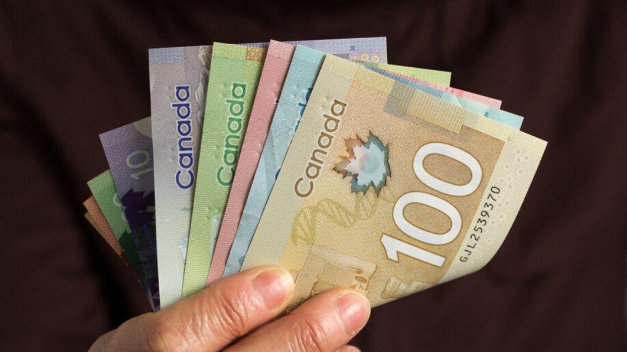 Une main tient des billets d'argent canadien.