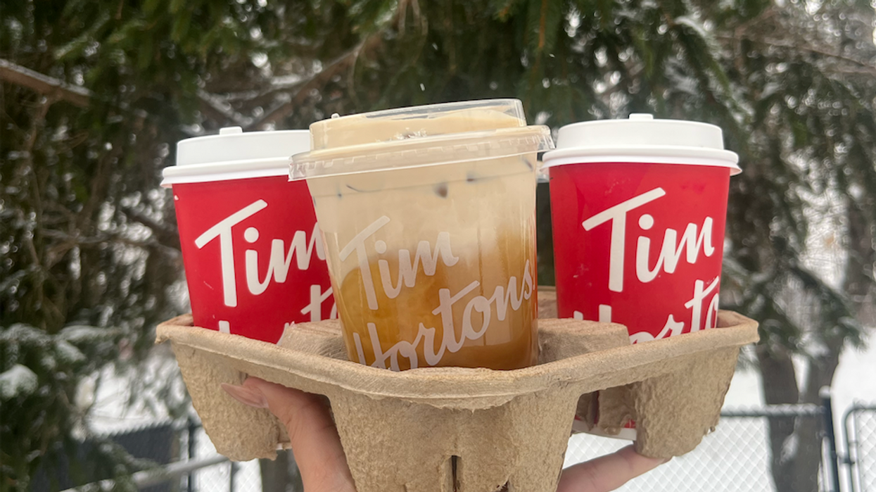Une main tient des breuvages du Tim Hortons.
