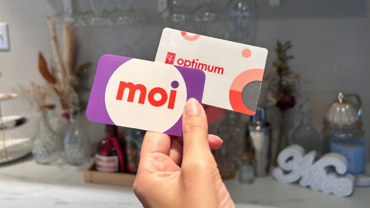 Une main tient deux cartes ; l'une où il est inscrit moi et l'autre PC Optimum.