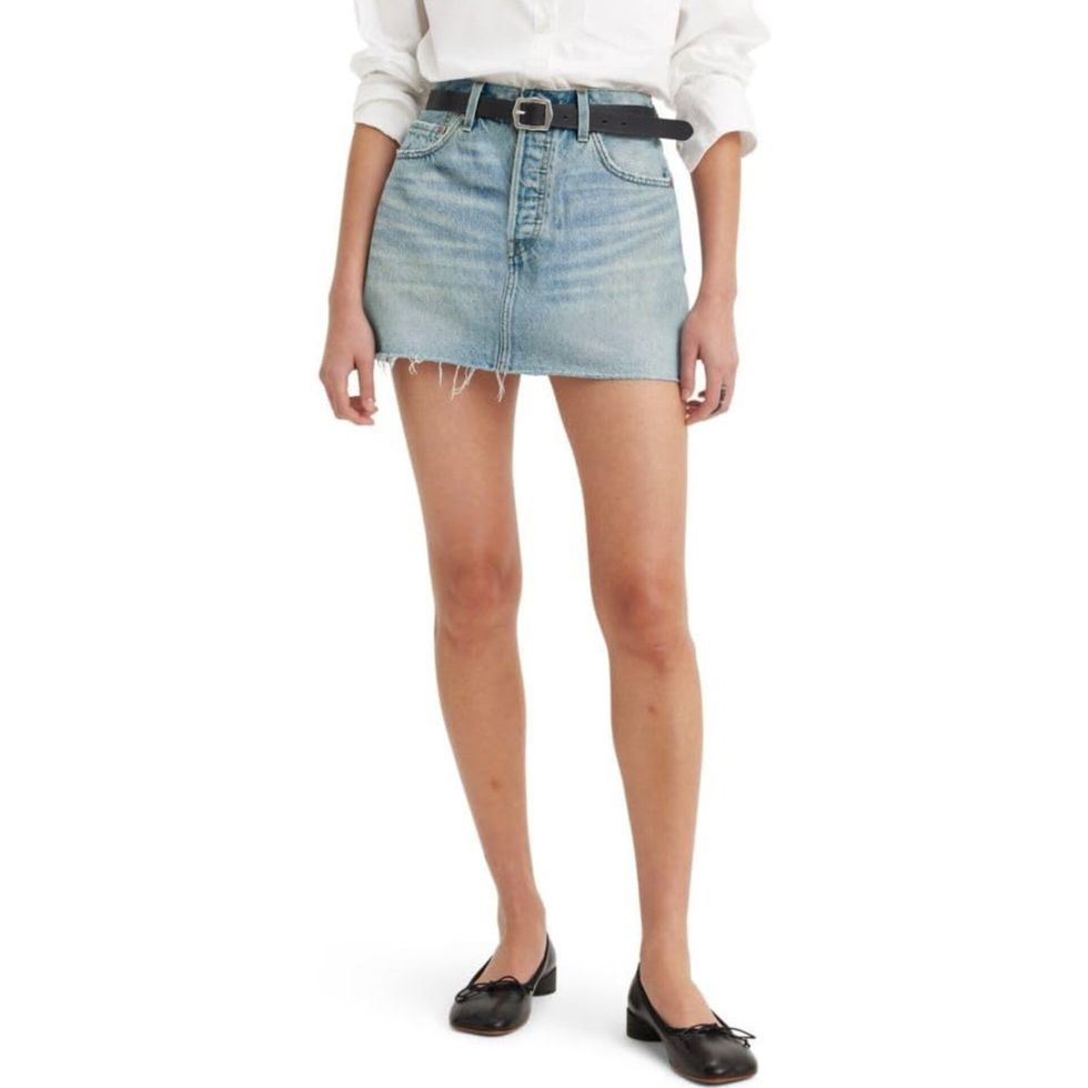 Une mannequin qui porte une mini jupe en denim de marque Levi's sur fond blanc.