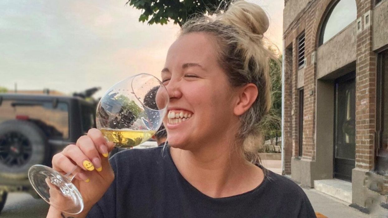 Une personne buvant un verre de vin sur la terrasse de la brasserie EtOH, dans Villeray.