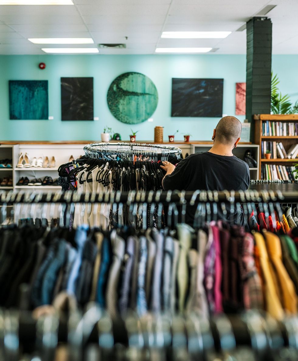 Une personne devant un pr\u00e9sentoir de v\u00eatements.