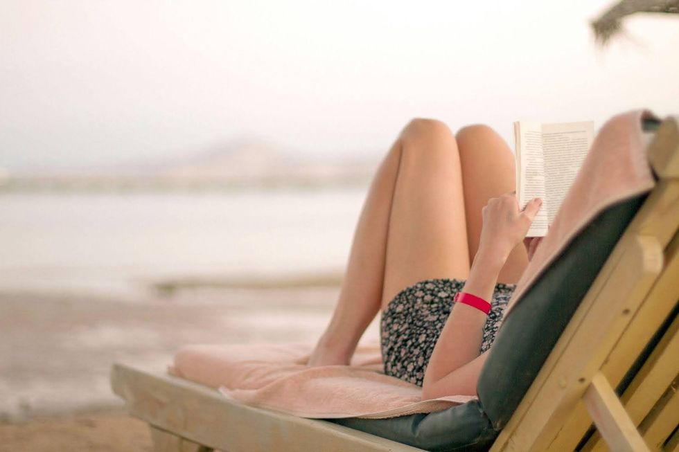 Une personne lisant un livre dans une chaise longue sur la plage.