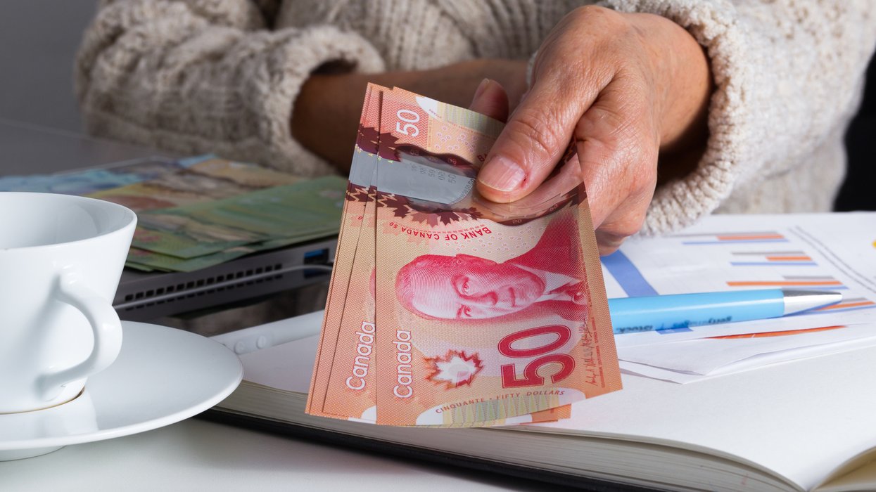 Une personne qui tient des billets d'argent canadien.