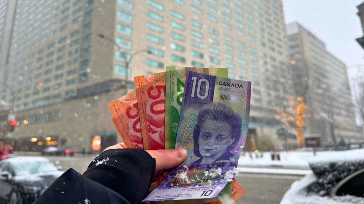 Une personne tenant des billets de 50 $, 20 $ et 10 $ dans sa main, avec la ville de Montréal en arrière-plan.