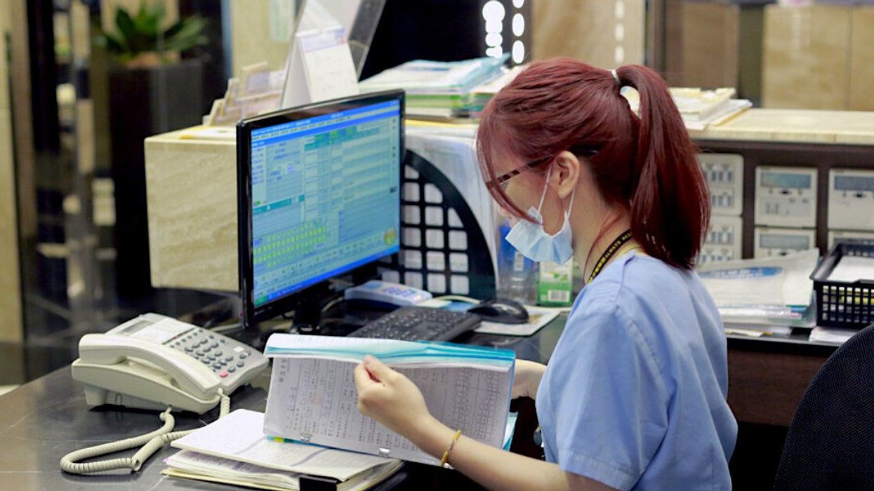 Une personne travaillant sur des dossiers, assise à un bureau devant un ordinateur.